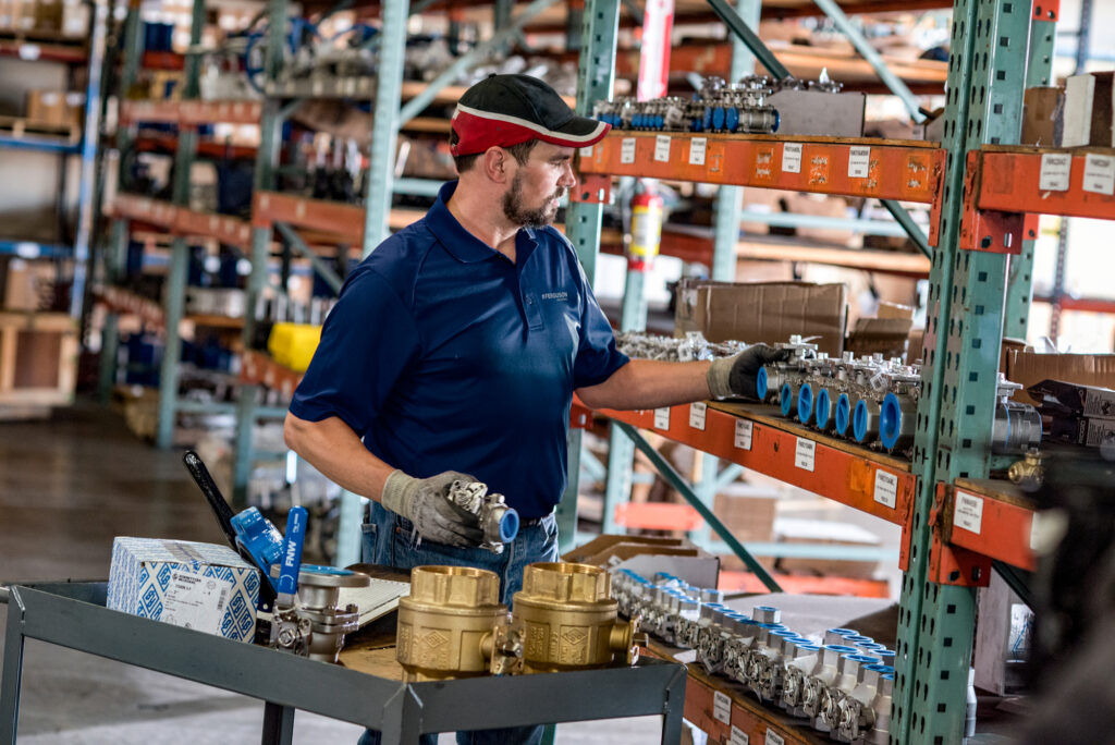 Nova Beltech warehouse specialist selecting industrial valves and MRO supplies from inventory storage racks