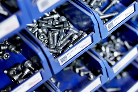 Industrial steel socket head cap screws and hardware stored in labeled blue storage bins by Nova Beltech